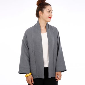 Peut inclure: Une veste en lin gris avec un col large et des manches longues. La veste est ouverte &agrave; l'avant et a une coupe ample.