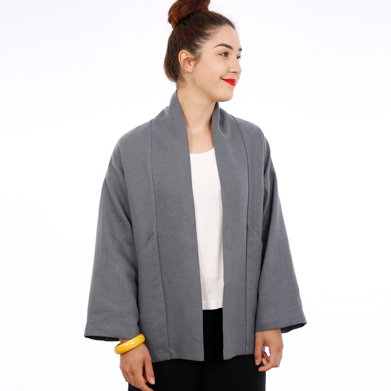 Peut inclure: Une veste en lin gris avec un col large et des manches longues. La veste est ouverte &agrave; l'avant et a une coupe ample.