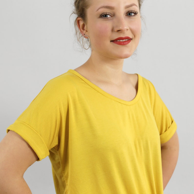 May include: A yellow short-sleeved t-shirt with a v-neck and rolled up sleeves.