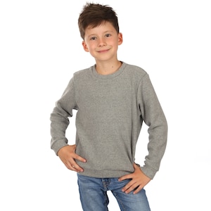 May include: A young person wearing a gray sweatshirt and blue jeans. They are standing with their hands on their hips and looking at the camera.