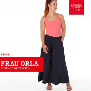 Pode incluir: Uma mulher vestindo um top rosa sem mangas e calças azuis de perna larga. O texto "FRAU ORLA HOSE MIT WEITEM BEIN" está em um retângulo vermelho. O texto "STUDIO SCHNITT REIF" está em um retângulo vermelho.