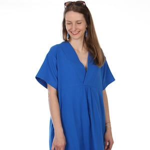 Op de afbeelding: Een helderblauwe jurk met een V-hals en korte mouwen. De jurk heeft een losse pasvorm en een eenvoudig ontwerp. Zonnebril op het hoofd van de persoon. De jurk is gemaakt van een zachte, soepele stof.