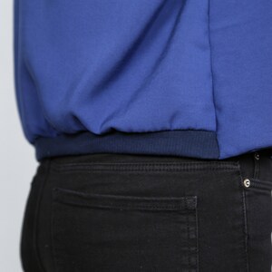 Pode incluir: Uma jaqueta azul com uma cintura de malha azul marinho. A jaqueta &eacute; usada sobre cal&ccedil;as jeans pretas.
