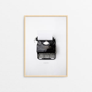 May include: A black vintage typewriter with a white sheet of paper in it. The typewriter is on a white background with a wooden frame. The text "CREATE" is printed below the typewriter.