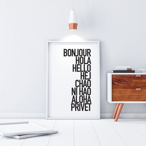 Puede incluir: Una impresión enmarcada blanca con las palabras "Bonjour", "Hola", "Hello", "Hej", "Ciao", "Ni Hao", "Aloha" y "Privet" en texto negro.