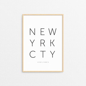 May include: A framed print with the text "NEW YORK CITY" and the coordinates "40.7128° N, 74.0060° W" in black text on a white background.