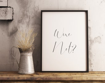 May include: A black framed print with the text "Wine Not?" in a cursive font. The print is sitting on a wooden shelf with a silver pitcher and dried grass.