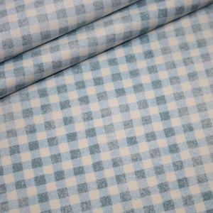 Puede incluir: Un primer plano de una tela de cuadros azules y blancos. La tela tiene una textura sutil y un fondo azul claro con cuadrados blancos.