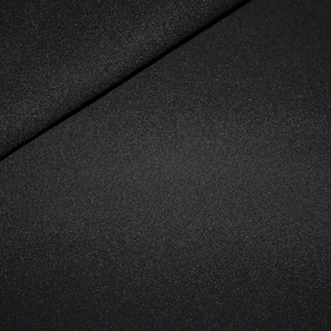 Könnte beinhalten: Nahaufnahme eines schwarzen Stoffes mit einer dezent strukturierten Oberfläche. Der Stoff ist diagonal gefaltet, wodurch zwei verschiedene Abschnitte entstehen. Das Material scheint undurchsichtig und nicht reflektierend zu sein, mit einem matten Finish. Der Gesamteindruck ist ein dunkles, festes Textil.