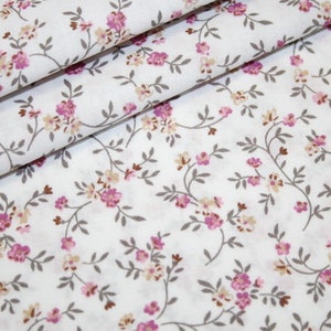 May include: White fabric with a small floral pattern. The flowers are pink and beige and are arranged in a repeating pattern on a white background.