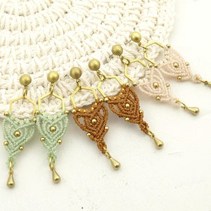 Peut inclure: Un ensemble de quatre paires de boucles d'oreilles faites à la main avec un design géométrique de style macramé. Les boucles d'oreilles sont réalisées dans une variété de couleurs, notamment le vert, le marron et le blanc.