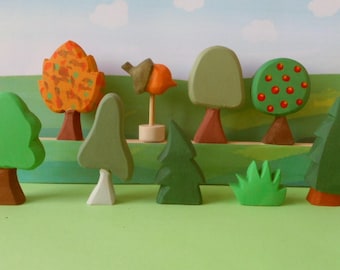 Könnte beinhalten: Ein Set aus Holzspielzeugbäumen in verschiedenen Farben und Stilen, darunter ein grüner Baum mit braunem Stamm, ein rot-grüner Baum mit roten Äpfeln, ein grüner Baum mit weißem Stamm und ein brauner Baum mit orangefarbenen Blättern.