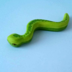 Könnte beinhalten: Eine grüne Spielzeugschlange aus Plastik mit einer strukturierten Oberfläche. Die Schlange ist in einer 'S'-Form gekrümmt.