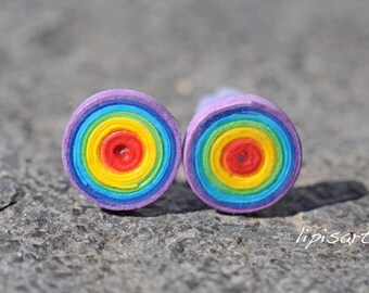 Könnte beinhalten: Zwei handgefertigte Ohrstecker mit einem Regenbogenspiralendesign. Die Ohrringe zeigen konzentrische Kreise in Rot, Orange, Gelb, Grün, Blau und Lila. Die Ohrringe sind auf einer grauen, strukturierten Oberfläche platziert.