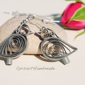 May include: A pair of silver earrings shaped like birds, made with paper quilling. The earrings are hanging from silver hooks.