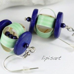 May include: A pair of earrings with blue and green paper rolled into a sphere shape. The earrings are attached to silver hooks.