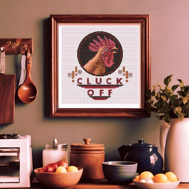 May include: A framed cross-stitch design featuring a rooster with the text "CLUCK OFF" in a red and black color scheme.
