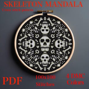 May include: A black and white cross-stitch pattern of a skeleton mandala in a wooden embroidery hoop. The design features skulls and bones. Text at the top reads "SKELETON MANDALA". The bottom text says "PDF", "100x100 Stitches", and "4 DMC Colors".