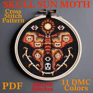 May include: A cross stitch pattern featuring a skull sun moth with 11 DMC colours. The pattern is 100x100 stitches and is displayed in a wooden embroidery hoop.