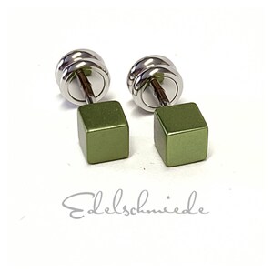 Könnte beinhalten: Ein Paar grüne quadratische Ohrstecker mit silbernen Stiften. Die Ohrringe sind aus Metall und haben eine matte Oberfläche.