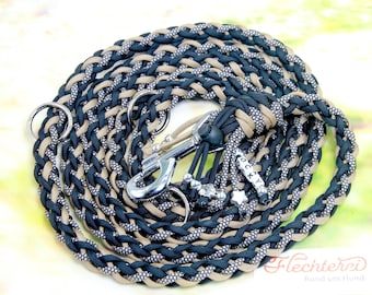 May include: A braided dog leash made of dark navy, tan, and reflective silver cord. The leash features a silver metal swivel snap hook, two metal rings, and decorative charms including star shapes and beads spelling the name ROCKY.