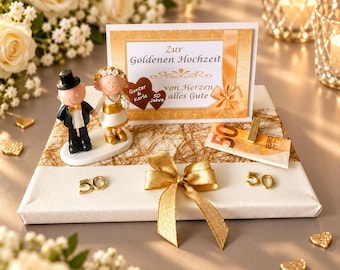 May include: A golden wedding anniversary gift display featuring a figurine of a couple, a card with the text Zur Goldenen Hochzeit von Herzen alles Gute, a 50 Euro banknote, a gold ribbon, and two gold 50 number accents on a white base.
