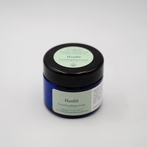May include: A blue jar with a black lid containing a facial care cream. The label on the jar reads "Hanf&ouml;l Gesichtspflegecreme".