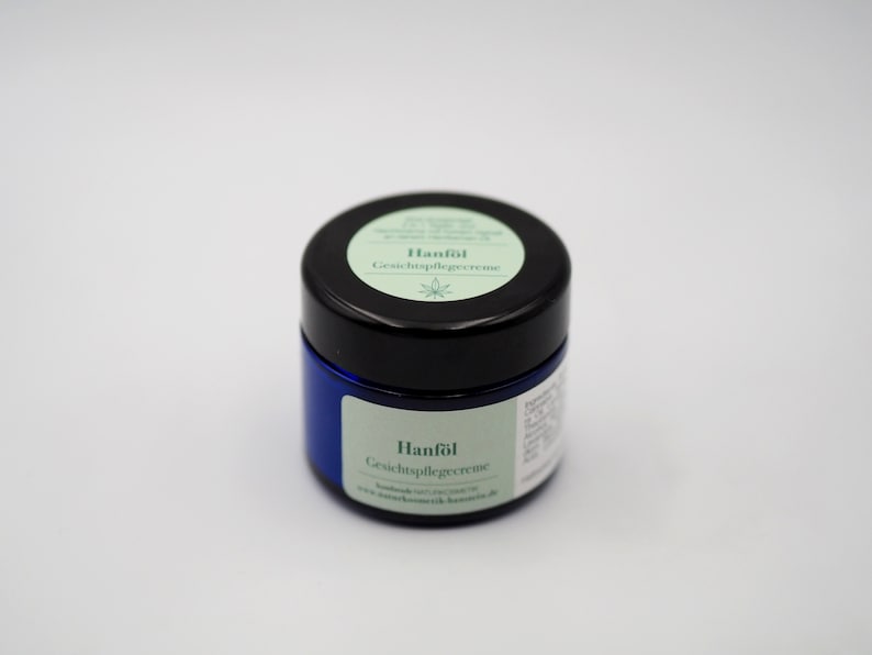 May include: A blue jar with a black lid containing a facial care cream. The label on the jar reads "Hanf&ouml;l Gesichtspflegecreme".