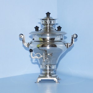 Peut inclure: Une samovar en argent avec des accents noirs et un bec verseur. La samovar est une bouilloire à thé russe traditionnelle.