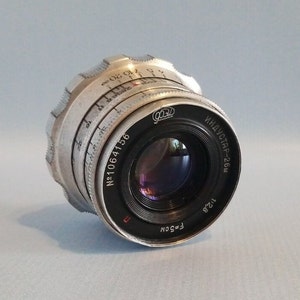 May include: A silver and black Industar-26M lens with a serial number of "No.1064156" and a maximum aperture of f/2.8. The lens is designed for 35mm film cameras.