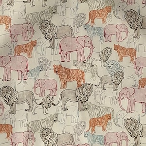 Op de afbeelding: Een stof met een herhaald patroon van verschillende dieren, waaronder leeuwen, tijgers en olifanten. De dieren zijn in tinten oranje, roze, grijs en blauw, tegen een witte achtergrond. Het ontwerp is een mix van gedetailleerde en omrande illustraties.