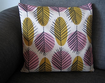 May include: A square throw pillow featuring a repeating pattern of mustard yellow and light pink circles. Each circle contains a dark navy blue line drawing of a palm leaf. The background of the pillow cover is an off-white cream color.