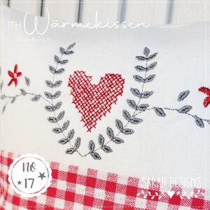 Op de afbeelding: Een rode hart met een grijze, bladerrijke krans borduurwerk op een witte stof met een rood-wit geruit patroon. De tekst "ITH W&auml;rmekissen 16cm & 20cm" staat bovenaan de afbeelding. De tekst "no * 17 *" staat in een cirkel linksonder in de afbeelding. De tekst "SARAH DESIGNS" staat rechtsonder in de afbeelding.