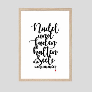 May include: A framed print with black calligraphy that reads "Nadel und Faden halten die Seele zusammen" with a small red heart at the bottom.