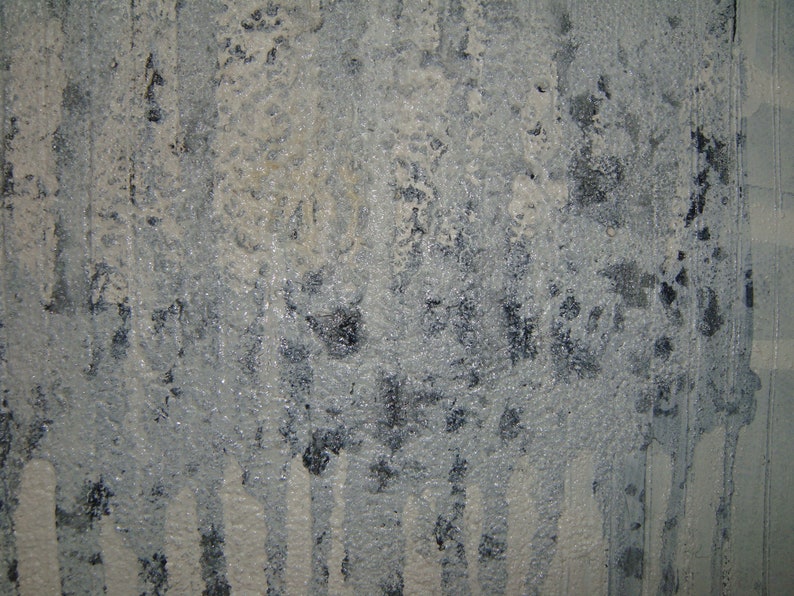 May include: A close-up of a textured, gray surface with white paint streaks. The surface has a rough, uneven texture and appears to be made of concrete or plaster.