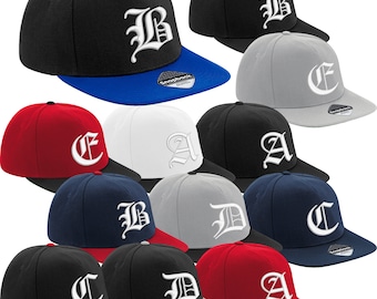 May include: A collection of snapback baseball caps in various colors, including black, red, navy, and gray. Each cap features a white embroidered letter in a gothic font on the front, with a contrasting bill.