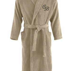 May include: A beige bathrobe with a shawl collar and a belt. The robe has the initials "C.B." embroidered on the front.