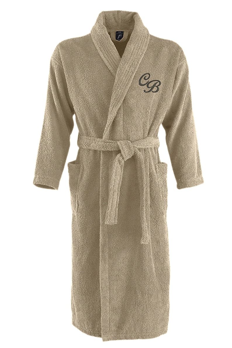 May include: A beige bathrobe with a shawl collar and a belt. The robe has the initials "C.B." embroidered on the front.