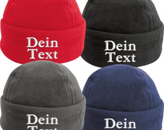 May include: Four fleece beanies in red, black, gray, and navy blue. Each beanie has the embroidered text "Dein Text" in white. The beanies are displayed on a white background.