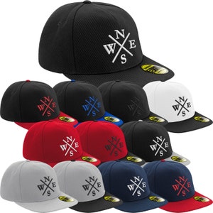 Könnte beinhalten: Eine Sammlung von 10 flachen Baseballkappen in verschiedenen Farben, jede mit einem weißen gestickten Kompass-Design mit den Buchstaben "WXE" und "S" in einem Kreuzmuster.