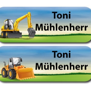 Op de afbeelding: Twee gele naamlabels voor bouwvoertuigen met een blauwe lucht en groene gras achtergrond. De naamlabels tonen een gele graafmachine en een gele shovel. De naam "Toni Mühlenherr" is in zwart op elk label gedrukt.