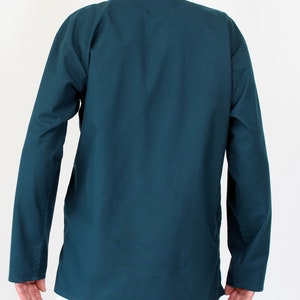 May include: A teal-colored long-sleeve shirt with a mandarin collar. The shirt has a relaxed fit and is made of a solid, opaque fabric. The sleeves are long and end at the wrists. The shirt is a solid color and has a simple, minimalist design.
