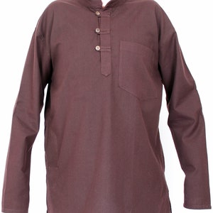 May include: A long-sleeved, brown tunic shirt with a mandarin collar and a single chest pocket. The shirt features three wooden buttons down the placket and a relaxed fit. The fabric appears to be a lightweight cotton or linen blend.