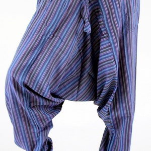 May include: Harem pants with a striped pattern in shades of blue, purple, and black. The pants have a drawstring waist and pockets. The loose fit and gathered ankles create a relaxed silhouette. The pants are made of a lightweight fabric.