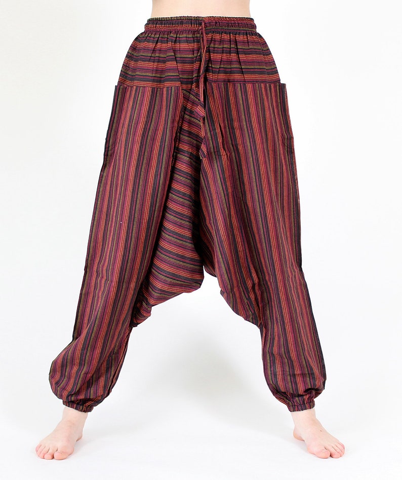May include: Striped harem pants in shades of red, black, and yellow. The pants feature a drawstring waist, pockets, and elastic cuffs at the ankles. The loose-fitting design is made of a lightweight fabric.