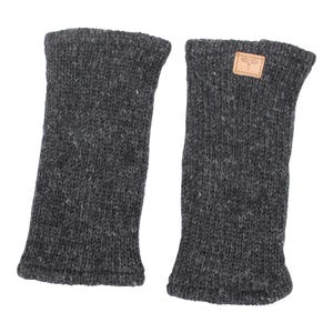 Könnte beinhalten: Ein Paar dunkelgraue Beinwärmer aus Strick. Die Beinwärmer sind aus einem dicken, strukturierten Garn gefertigt und haben einen gerippten Bund oben und unten. Einer der Beinwärmer hat ein kleines, rechteckiges Lederpatch mit einem Libellen-Design.