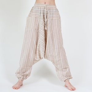 May include: Cream-colored harem pants with vertical stripes in shades of brown and red. The pants have a drawstring waist and elastic cuffs at the ankles. The loose, comfortable design is ideal for casual wear.