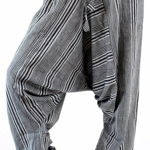 May include: Black and gray striped harem pants with a drawstring waist. The pants have a relaxed fit with a low crotch and pockets. The fabric features vertical stripes in varying widths.