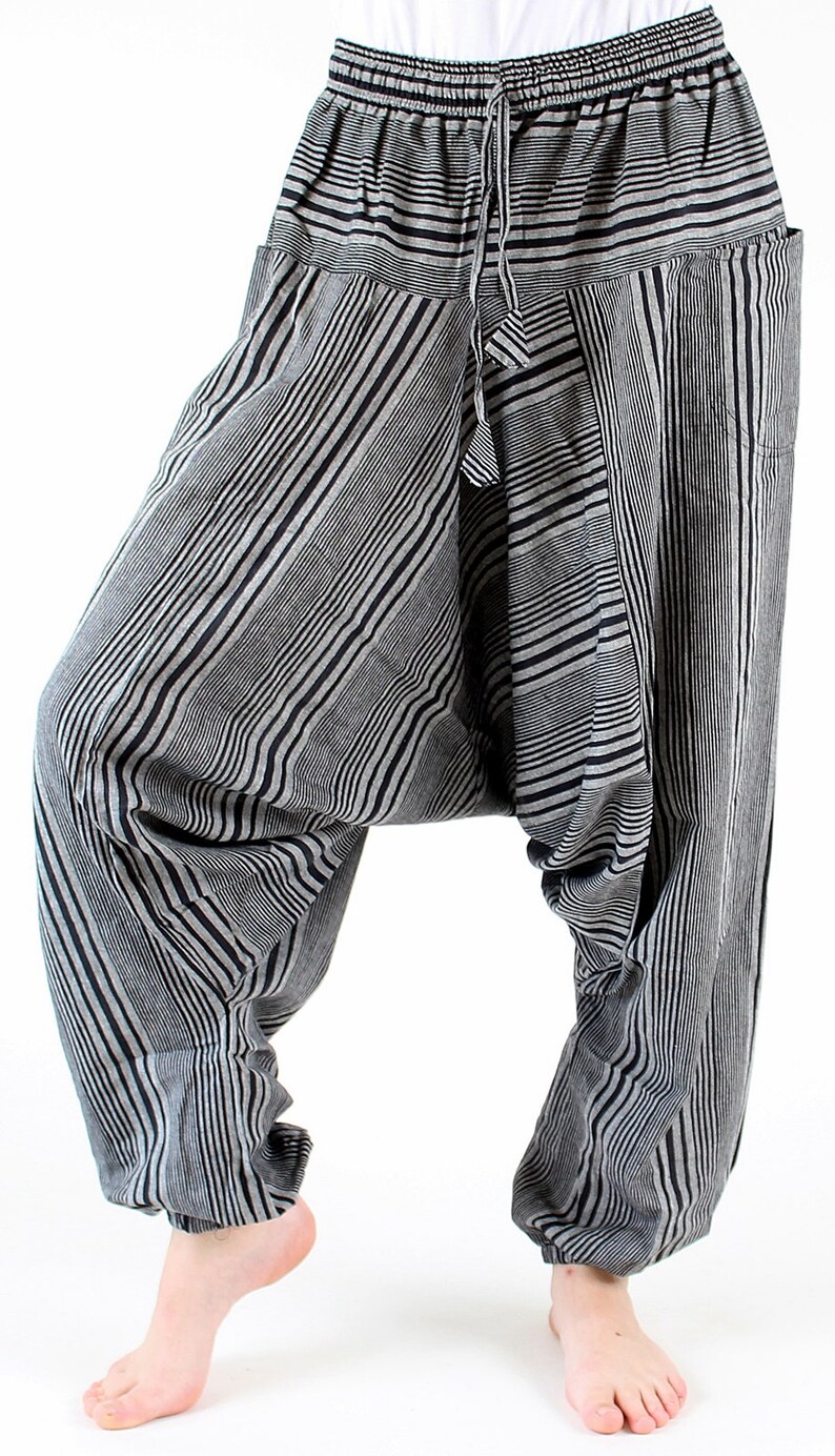 May include: Black and gray striped harem pants with a drawstring waist. The pants have a relaxed fit with a low crotch and pockets. The fabric features vertical stripes in varying widths.