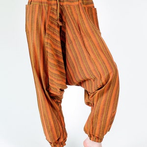 May include: Orange and brown striped harem pants with a drawstring waist and pockets. The pants have a relaxed fit and are made of a lightweight fabric. The pants are approximately 40 inches long.